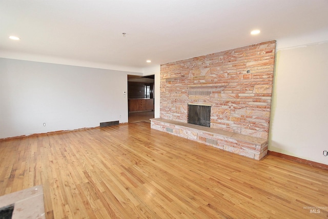 unfurnished living room with recessed lighting, visible vents, a stone fireplace, wood finished floors, and baseboards