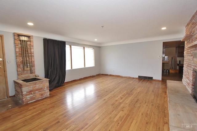 living room featuring light wood-style floors, recessed lighting, visible vents, and a fireplace