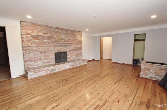 unfurnished living room with recessed lighting, a fireplace, baseboards, and wood finished floors