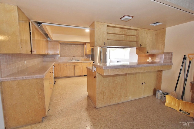 kitchen with light countertops, decorative backsplash, light brown cabinets, a sink, and a peninsula