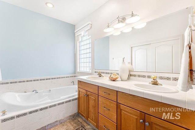 bathroom featuring tiled tub and vanity