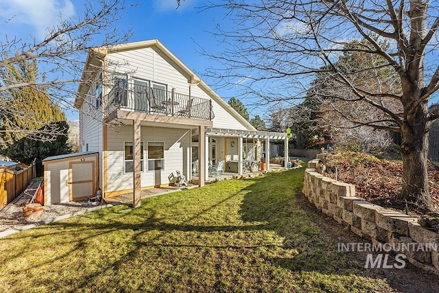 back of house with a balcony, a lawn, and a shed