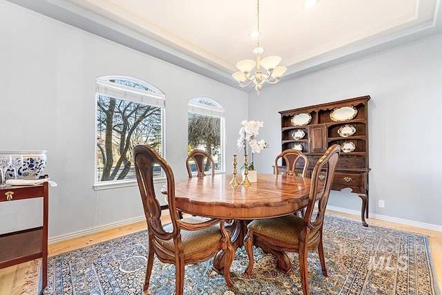 dining room with a raised ceiling, a chandelier, and wood-type flooring