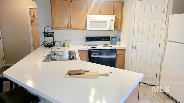 kitchen featuring a breakfast bar area, light countertops, a sink, white appliances, and a peninsula