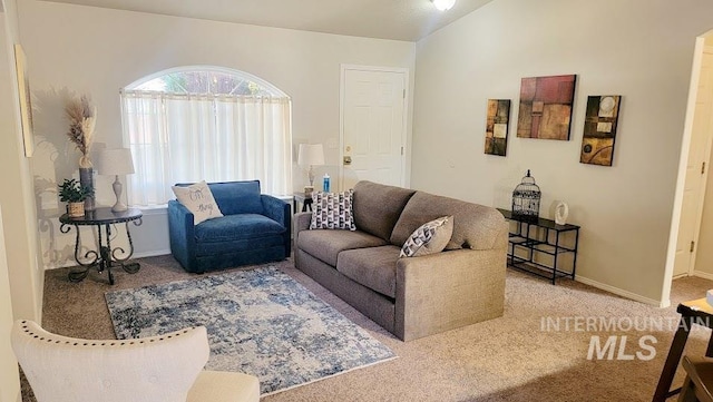 living area with carpet floors, vaulted ceiling, and baseboards