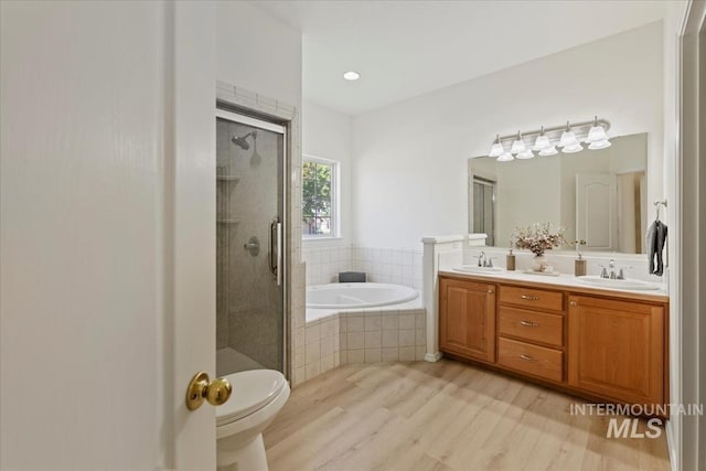 bathroom with wood finished floors, a garden tub, a shower stall, and double vanity
