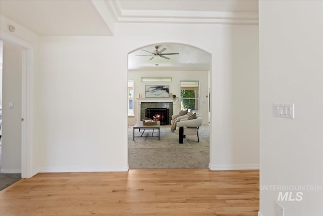 corridor with light wood-style flooring, arched walkways, and baseboards
