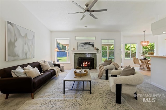 carpeted living room featuring ceiling fan, a tiled fireplace, and baseboards