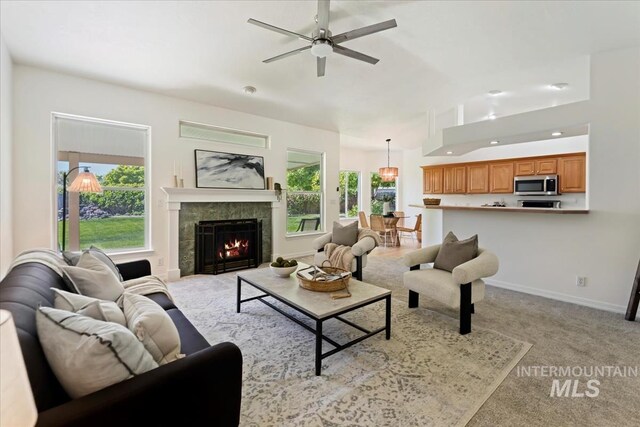 living room featuring ceiling fan, a fireplace, light carpet, recessed lighting, and baseboards
