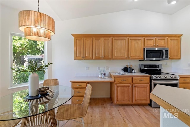 kitchen featuring stainless steel appliances, lofted ceiling, light countertops, light wood-type flooring, and decorative light fixtures
