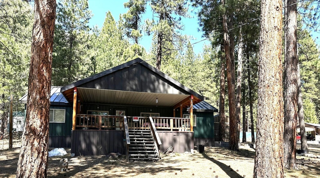 rustic home featuring stairs, a porch, a standing seam roof, and metal roof