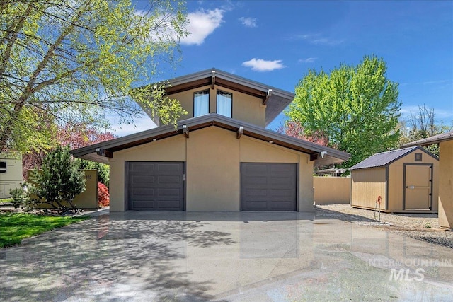 view of front of property featuring a storage unit, a garage, stucco siding, an outdoor structure, and driveway