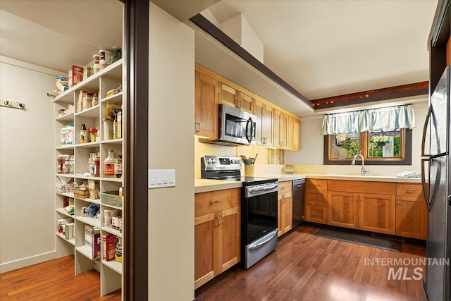 kitchen featuring light countertops, appliances with stainless steel finishes, dark wood-style floors, and a sink