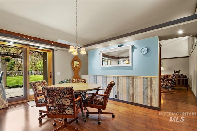 dining area featuring baseboards, wallpapered walls, wood finished floors, and visible vents
