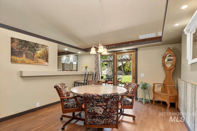 dining area with visible vents, baseboards, wood finished floors, and an inviting chandelier