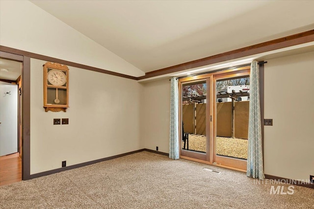 carpeted empty room featuring baseboards, vaulted ceiling, and visible vents