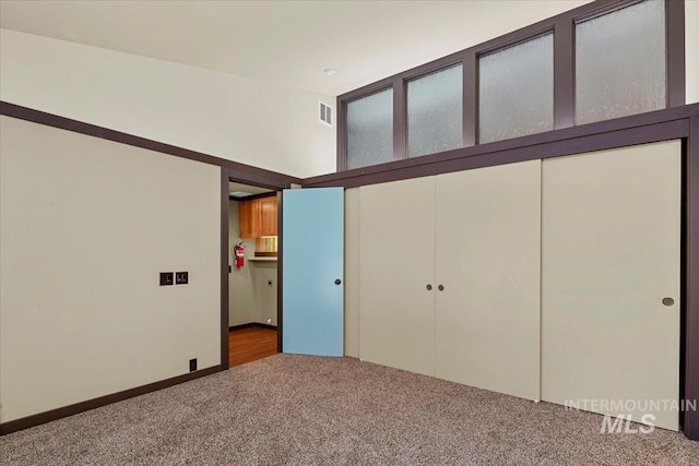 unfurnished bedroom featuring carpet floors, visible vents, and a closet