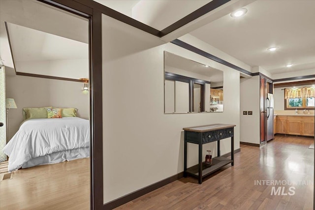 corridor featuring recessed lighting, baseboards, a sink, and wood finished floors