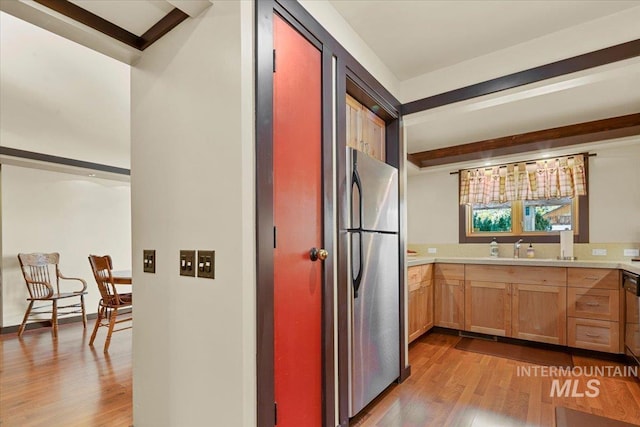 kitchen with light countertops, freestanding refrigerator, light wood-style flooring, and beam ceiling