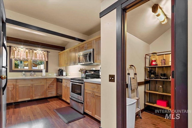 kitchen with appliances with stainless steel finishes, light countertops, light brown cabinets, vaulted ceiling with beams, and dark wood-type flooring