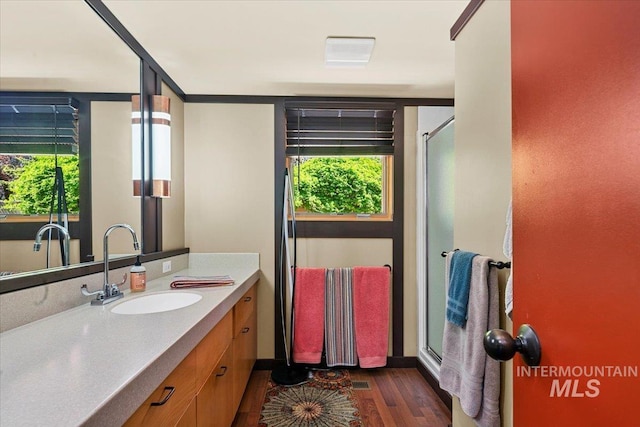 full bathroom featuring an enclosed shower, vanity, baseboards, and wood finished floors