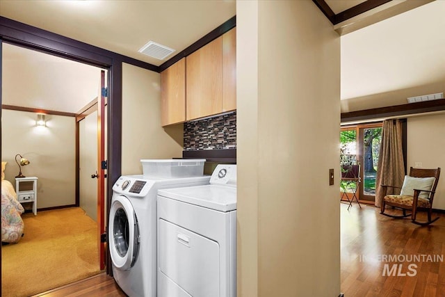 laundry area featuring visible vents, cabinet space, wood finished floors, and separate washer and dryer