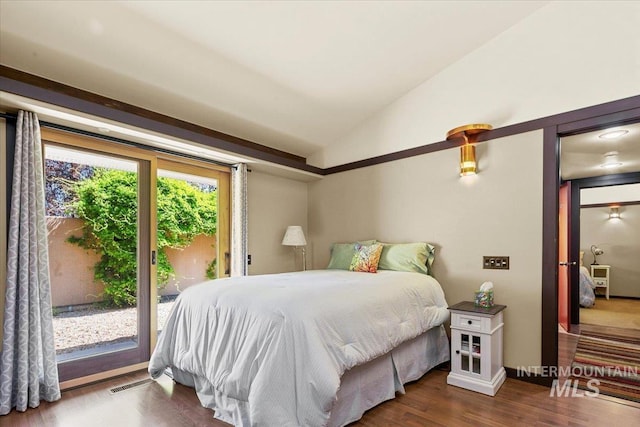 bedroom with access to outside, lofted ceiling, visible vents, and wood finished floors