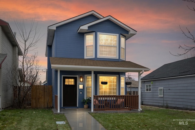 front facade with covered porch and a yard