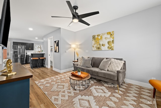 living room with ceiling fan and light hardwood / wood-style flooring