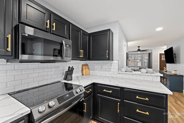 kitchen featuring light stone countertops, ceiling fan, stainless steel appliances, tasteful backsplash, and light wood-type flooring