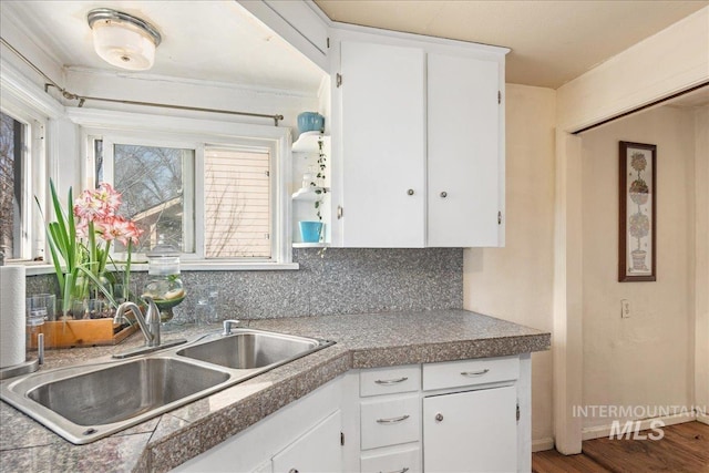 kitchen featuring tile countertops, white cabinets, backsplash, and a sink