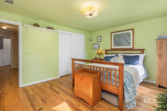 bedroom with visible vents, baseboards, light wood-style floors, and a closet