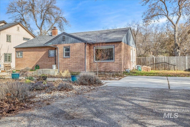 view of side of property with brick siding, a chimney, and fence