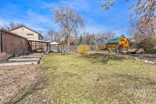 view of yard featuring a storage unit, an outbuilding, and a fenced backyard