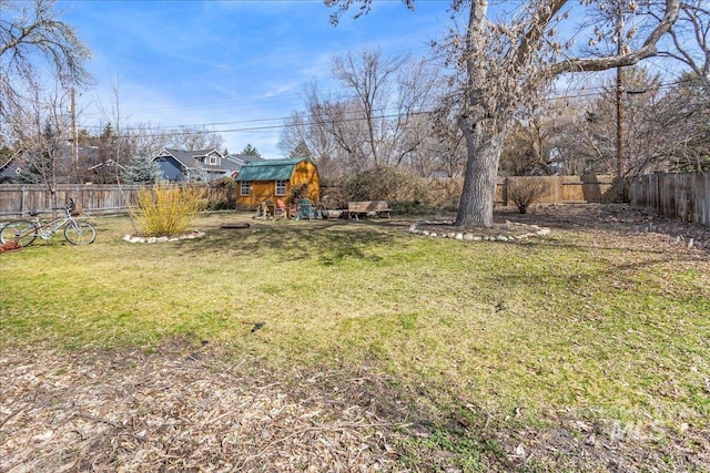 view of yard with an outbuilding, a fenced backyard, and a shed