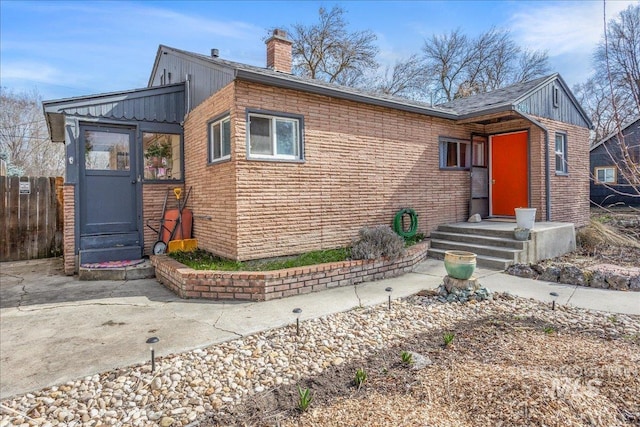 view of front of property with fence, brick siding, and a chimney