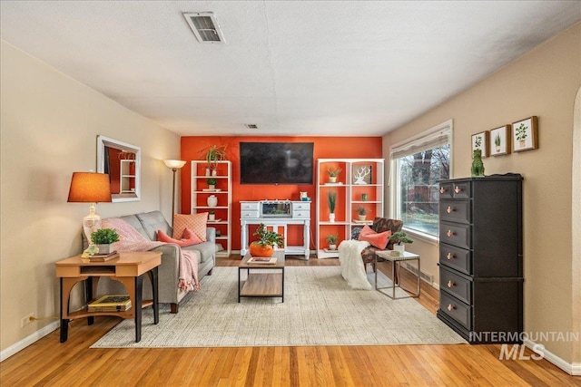 living area with wood finished floors, visible vents, and baseboards