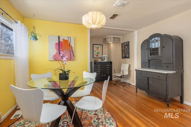 dining room featuring visible vents, baseboards, and wood finished floors