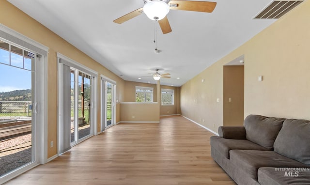 living area featuring light wood finished floors, baseboards, and visible vents