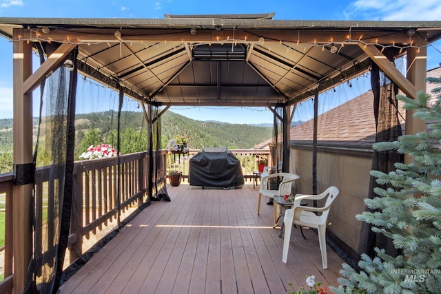 wooden deck featuring a forest view, grilling area, and a gazebo