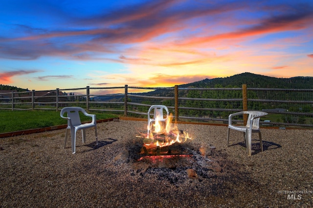 view of jungle gym featuring a fire pit, fence, and a mountain view