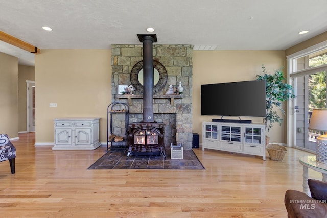 living room with a wood stove, visible vents, baseboards, and wood finished floors