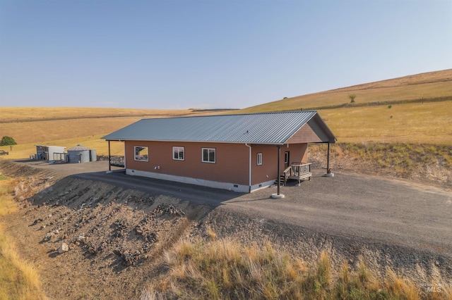 view of property exterior featuring crawl space, a rural view, and metal roof