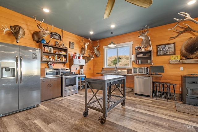 kitchen featuring wood finished floors, open shelves, stainless steel appliances, and wooden walls