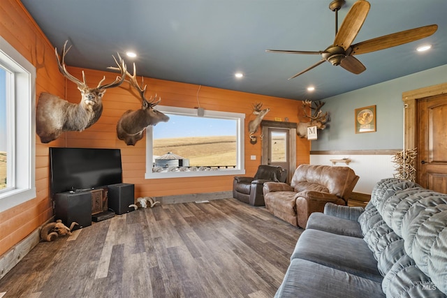 living room with wood walls, a ceiling fan, wood finished floors, and recessed lighting