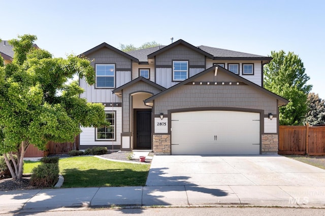 craftsman house with fence, concrete driveway, a front yard, a garage, and stone siding