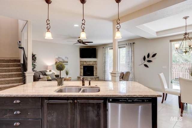 kitchen with dark brown cabinets, open floor plan, ceiling fan with notable chandelier, stainless steel dishwasher, and a sink