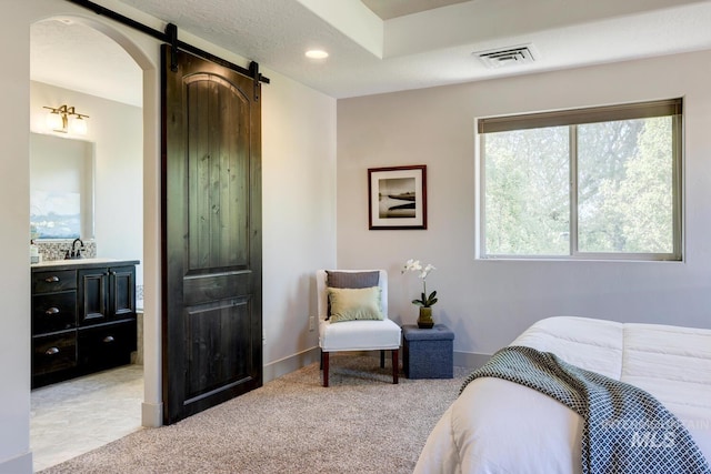 bedroom with arched walkways, visible vents, light colored carpet, and a barn door