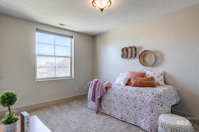 bedroom with baseboards, visible vents, a textured ceiling, and carpet