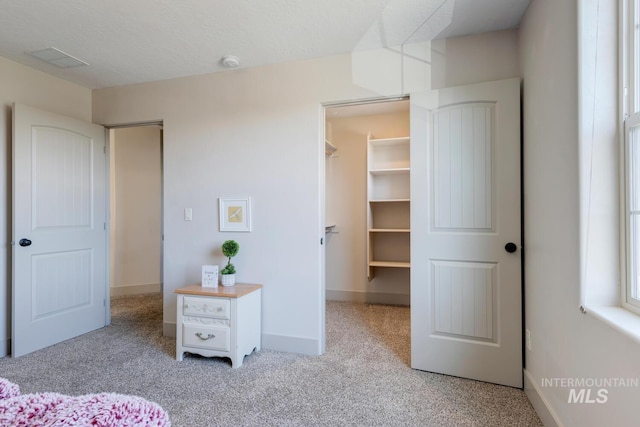 carpeted bedroom with visible vents, a textured ceiling, a closet, baseboards, and a spacious closet